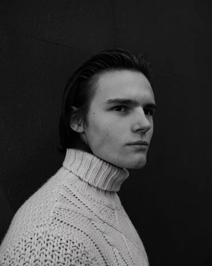 Portrait en noir et blanc d’un jeune homme en pull à col roulé