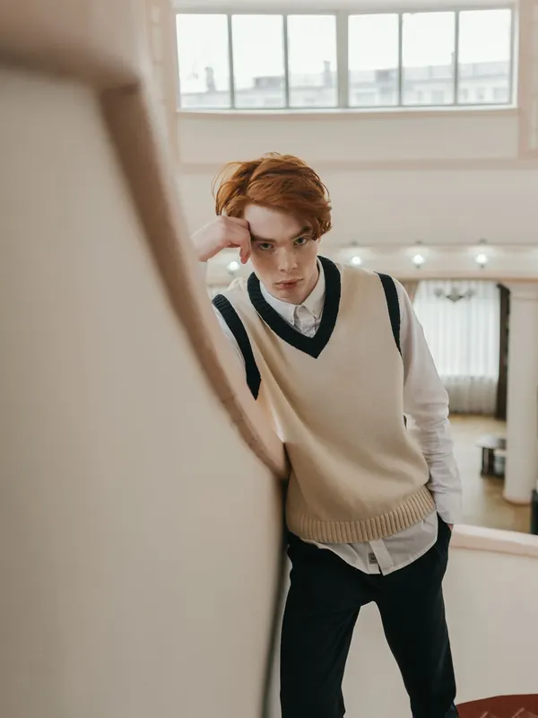 Jeune homme roux en pull sans manches sur une chemise blanche